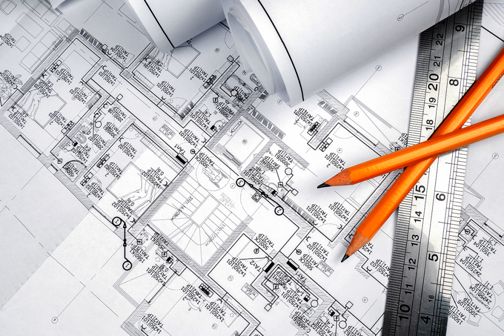 Vista superior de plantas arquitetônicas com rolos de desenhos, réguas e lápis sobre uma mesa